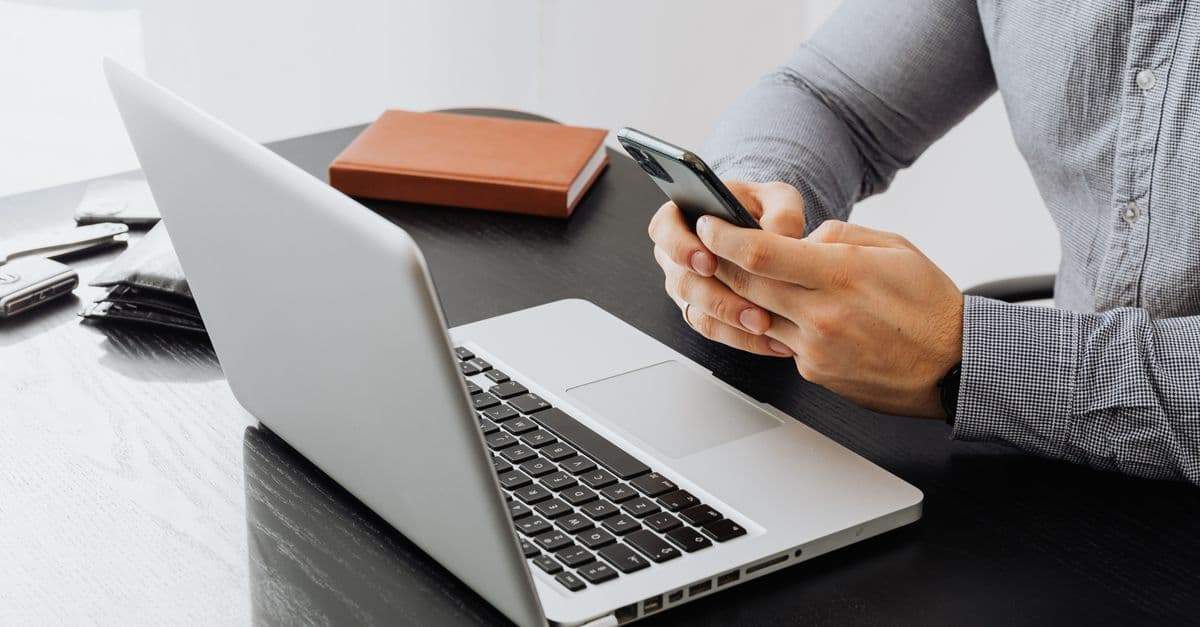 person calculating expenses with laptop and smartphone, modern vacation rental apartment background — Foto: https://kaboompics.com/ (Pexels)