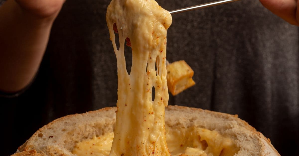 couple eating fondue by a fireplace in a cozy mountain cabin winter — Foto: Gonzalo Acuña (Pexels)