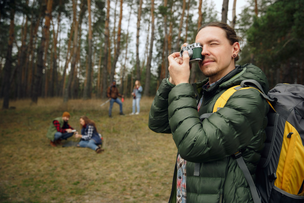 Homem tirando foto em uma floresta, com pessoas ao fundo